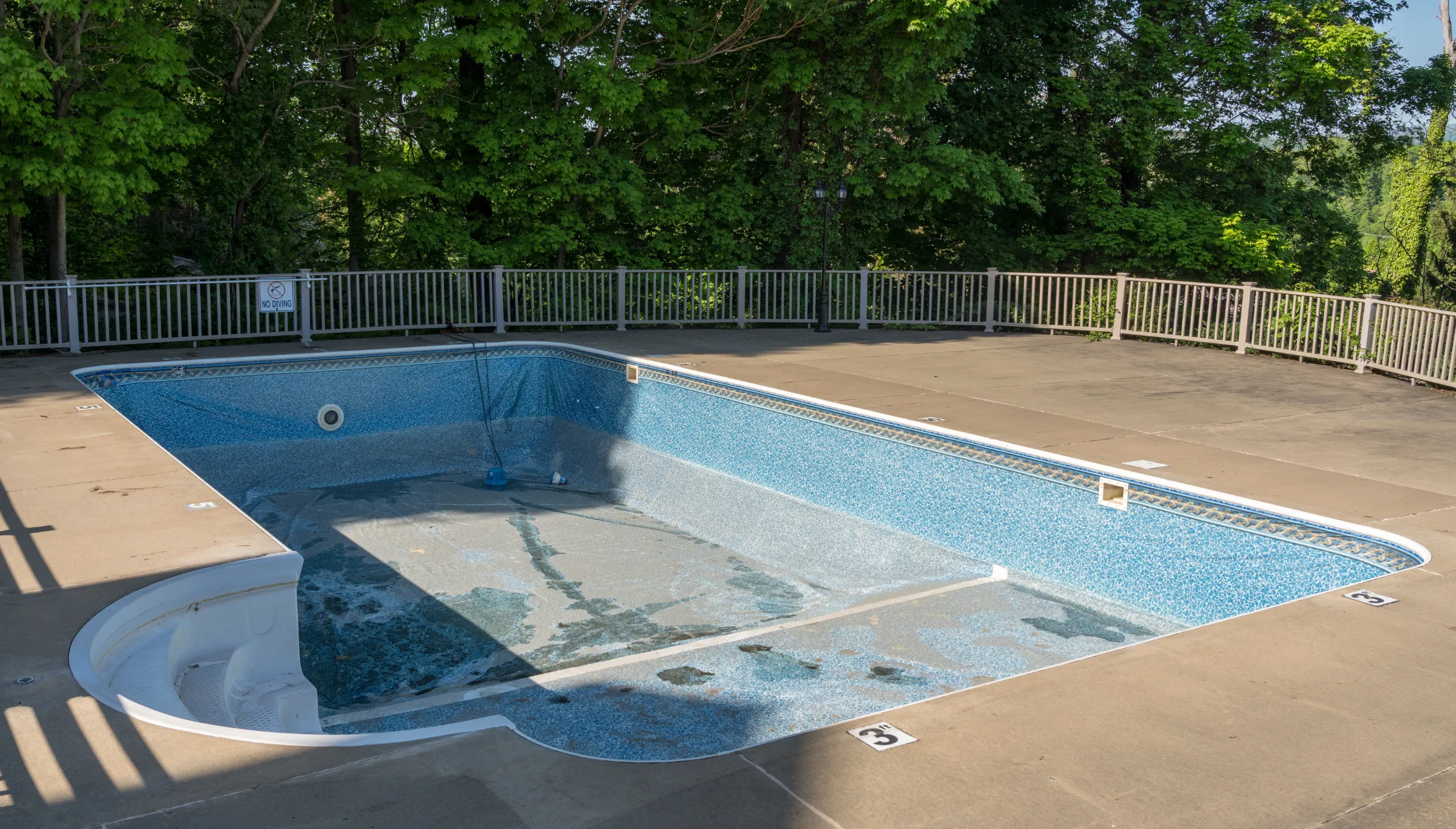 Old in-ground swimming pool in Dallas TX before demolition showing deteriorated pool structure