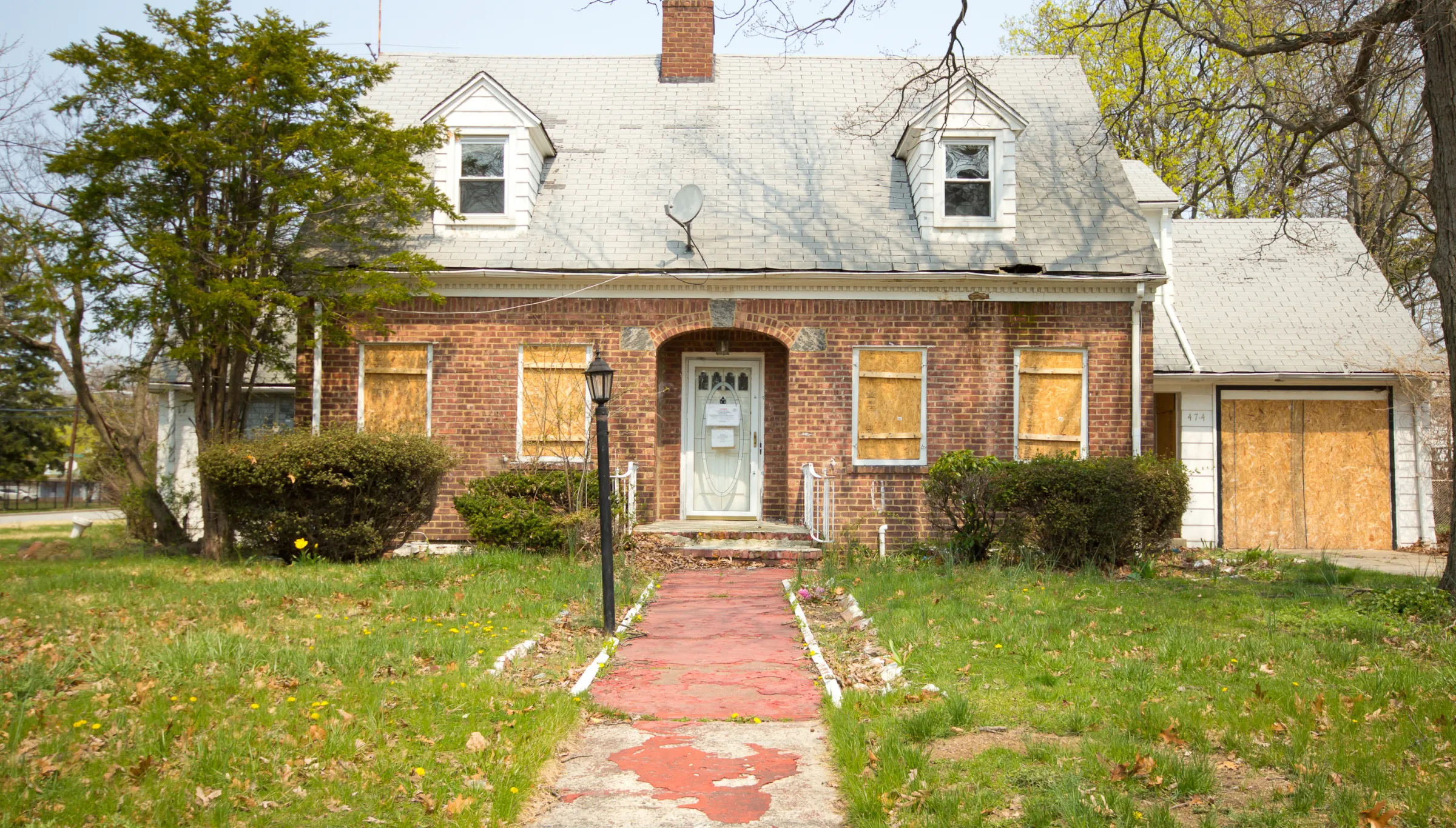 Old boarded residential house in Dallas TX before demolition showing abandoned property ready for teardown