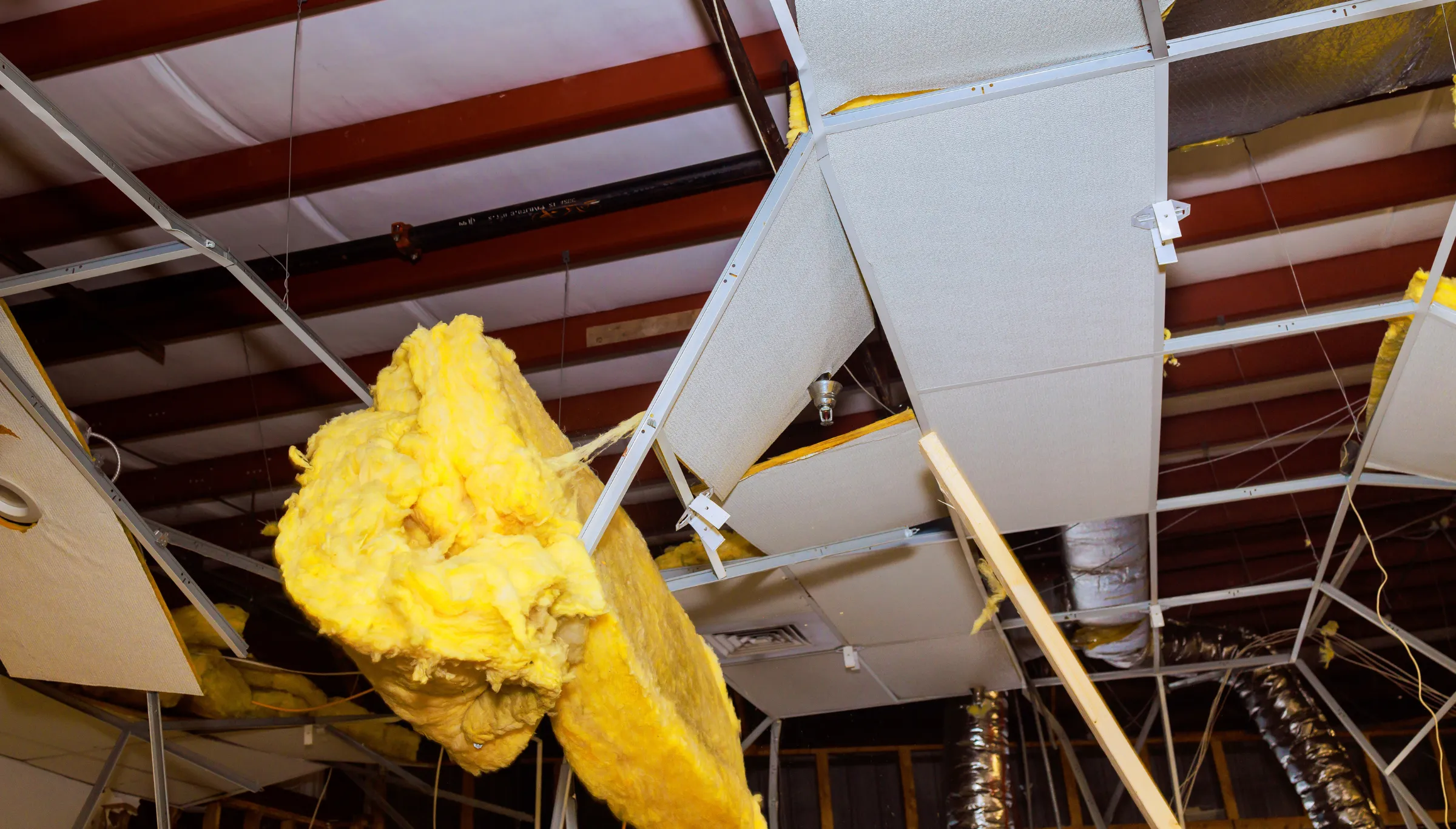 Commercial interior demolition in Dallas TX removing ceiling panels insulation and structural components inside commercial building renovation project