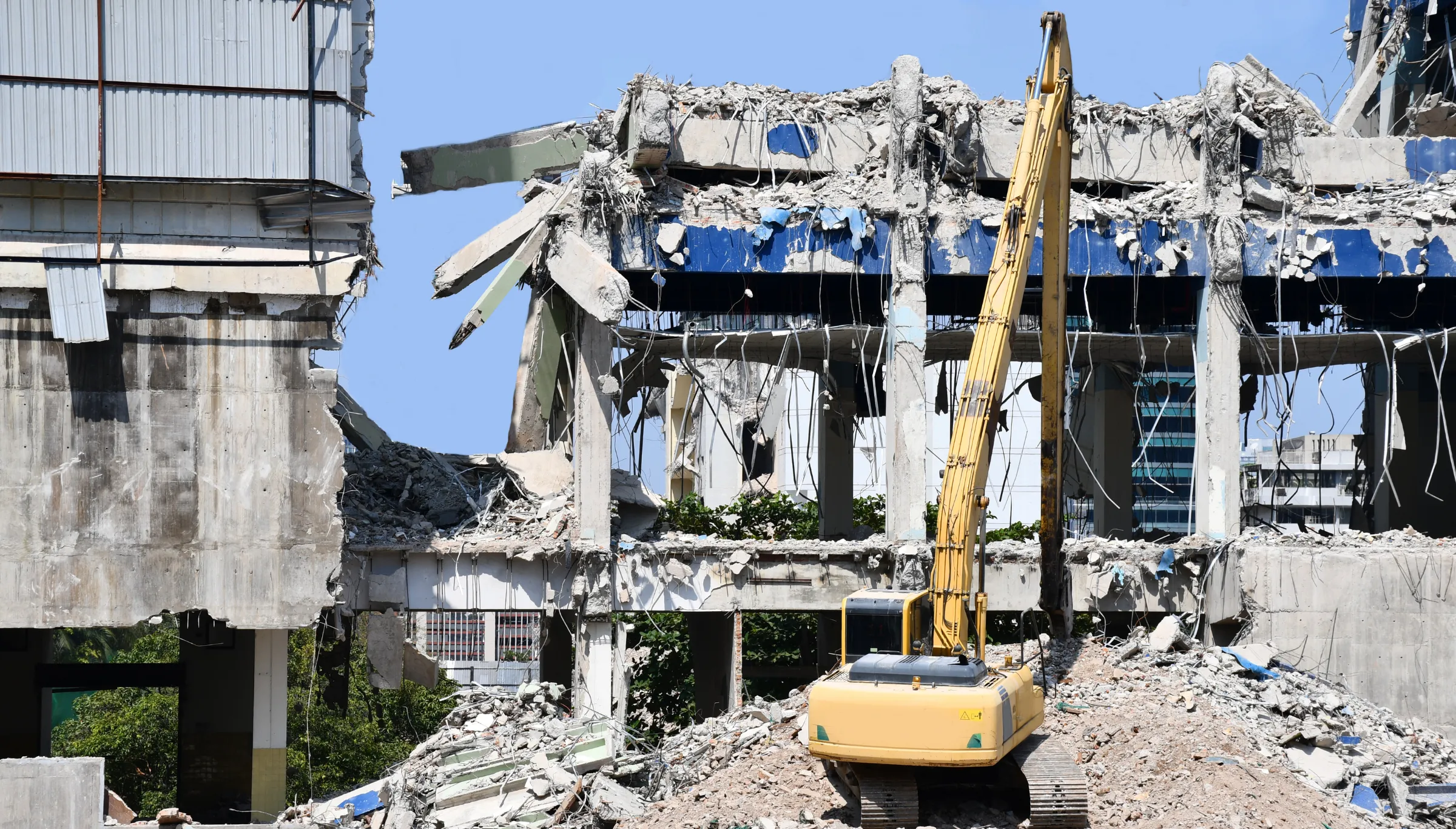 Commercial demolition in Dallas TX with excavator tearing down large concrete building structure and clearing debris from job site