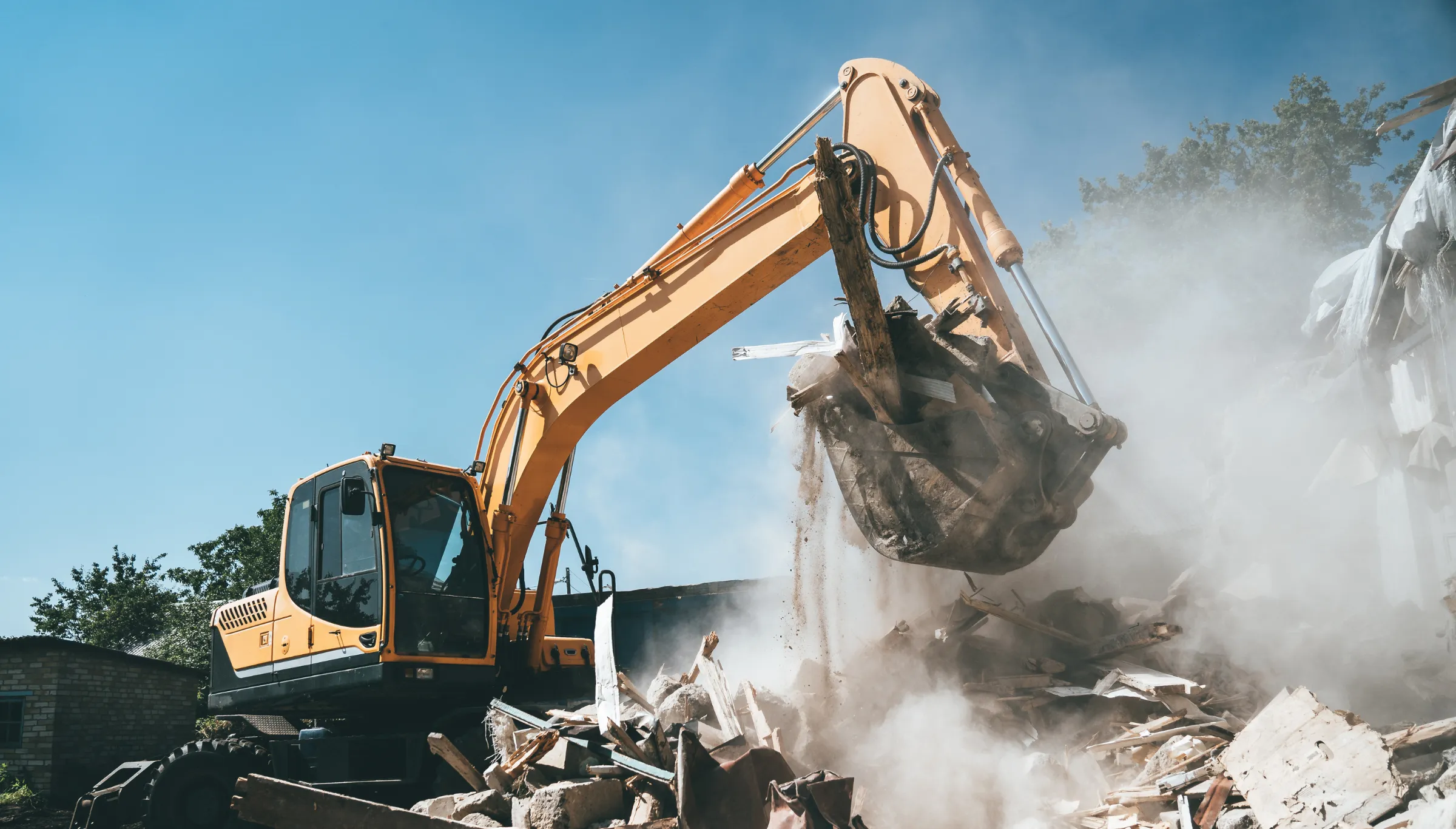 Full structure demolition in Dallas TX with excavator loading debris during complete building teardown and site clearing