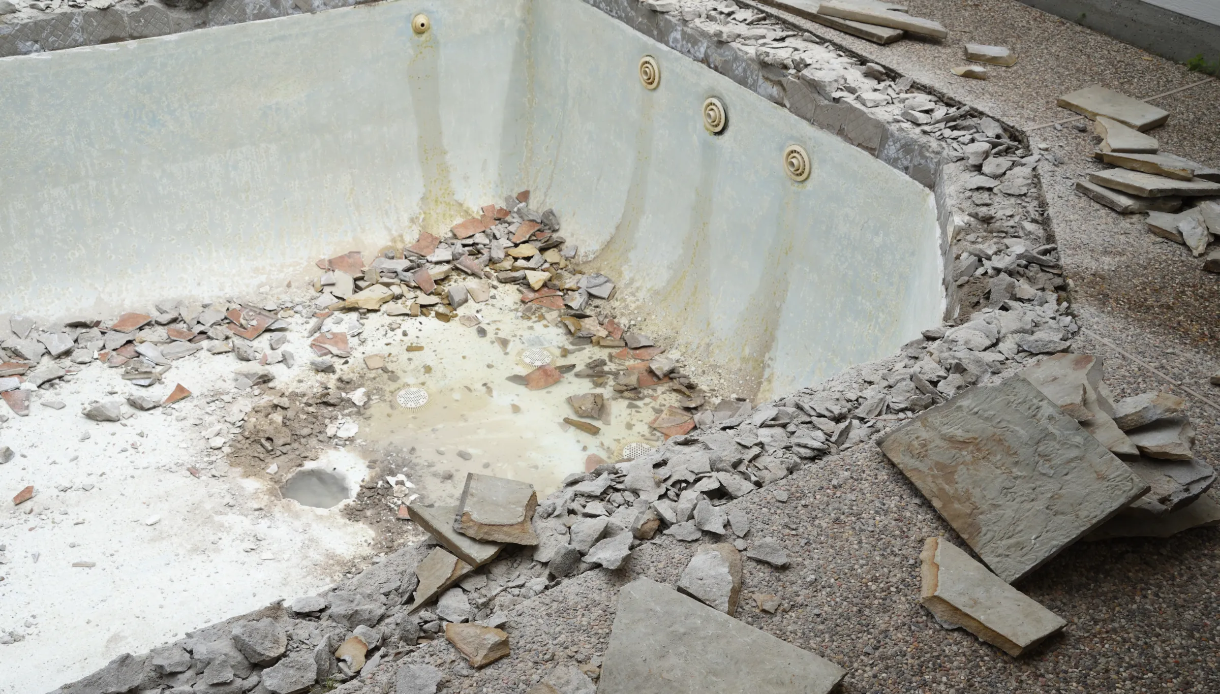 Pool demolition in Dallas TX showing broken concrete pool structure and debris during residential removal project